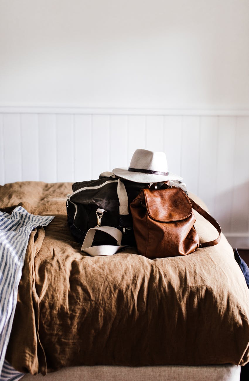 baggage with hat on soft bed in house